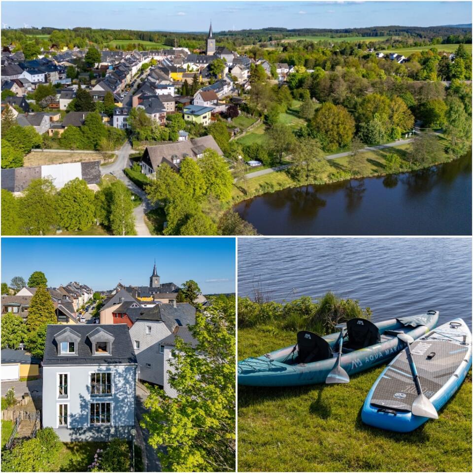 Luftaufnahmen und Nahaufnahmen einer Stadt in der Nähe eines Sees, mit Kirchturm, Häusern, üppigem Grün sowie zwei blauen Paddleboards und einem Kajak, die am grasbewachsenen Ufer in der Nähe des Ferienhauses „Die Blaue Pause“ liegen.