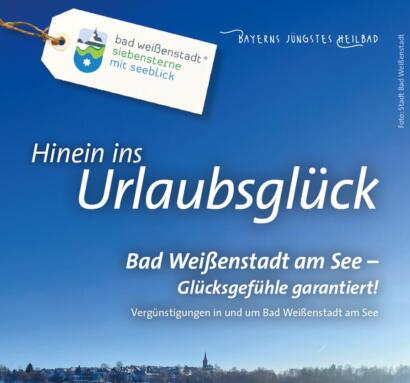 Blau-weiße Reiseanzeige mit einem See und einem verschneiten Dorf im unteren Bildbereich. Der Text wirbt für einen Urlaub in Bad Weißenstadt, Deutschland, und verspricht Glücksmomente, inspirierende Ausblicke auf den See sowie ausführliche Prospekte, die bei der Planung Ihres perfekten Urlaubs helfen.
